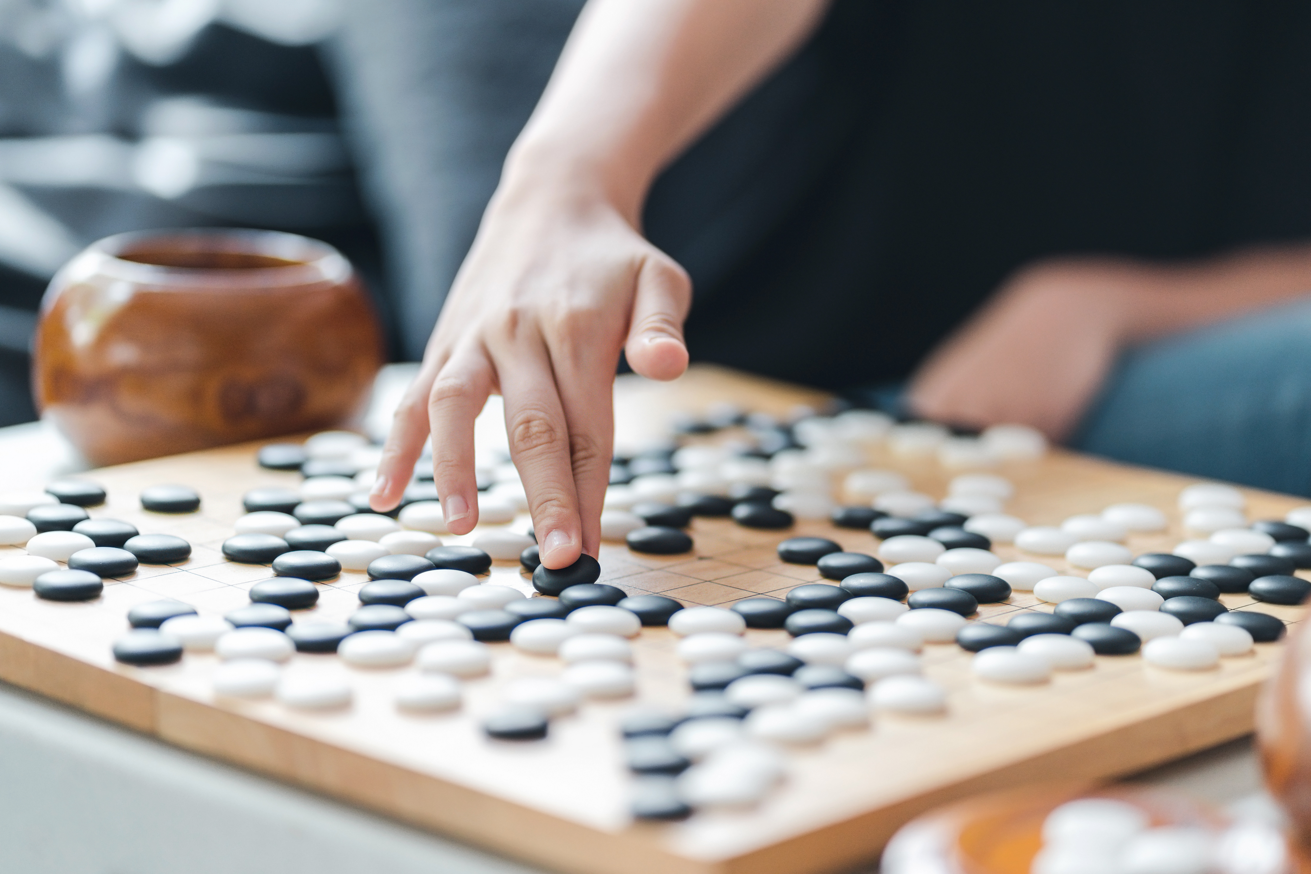 player's hand put stone on the game board - an ancient game also known as baduk in Korean, weiqi in Chinese and Igo in Japanese